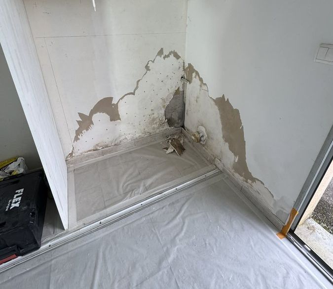 Mur dégradé après un dégât des eaux à Morre : enduit et peinture décollés en bas de cloison